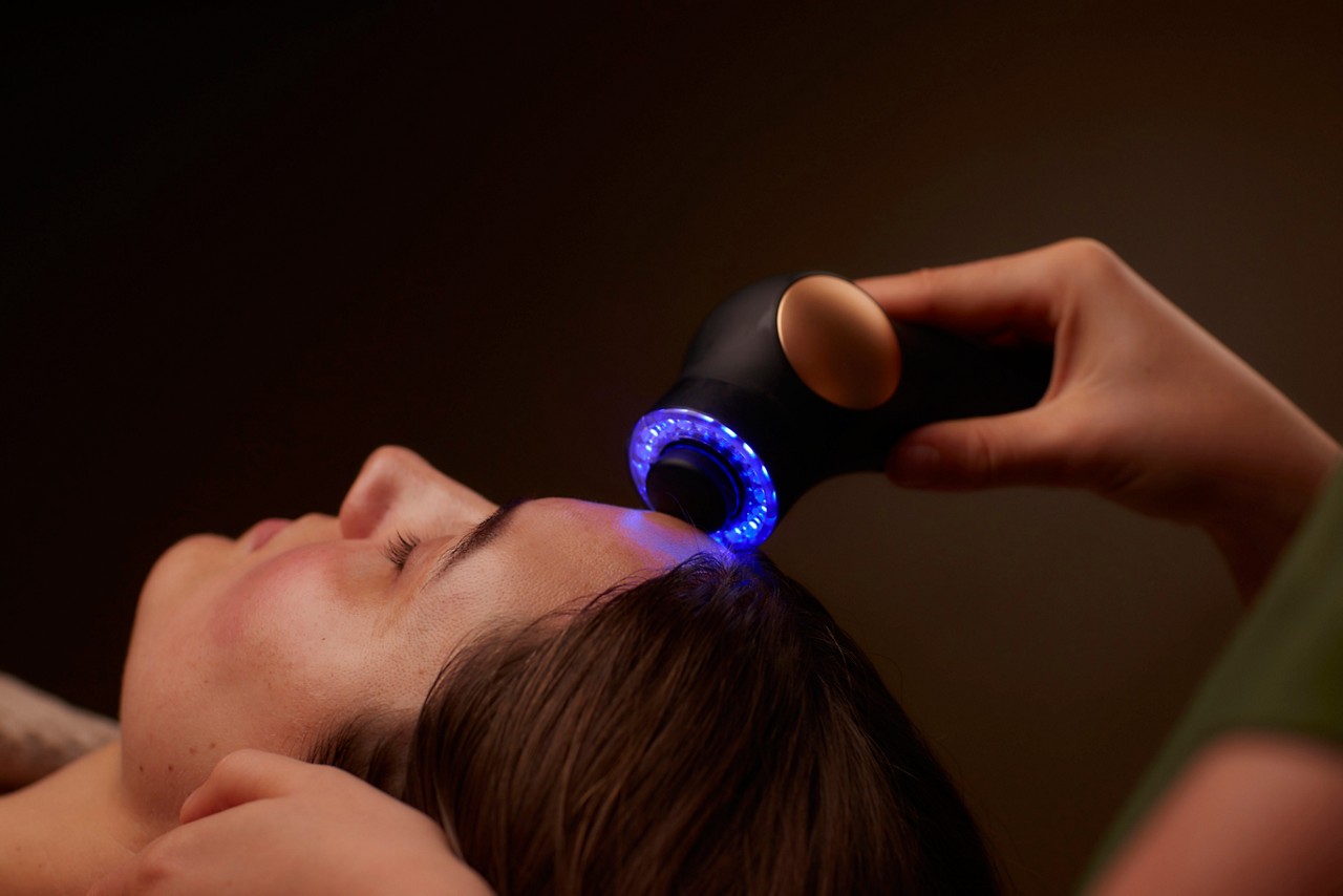 Spa therapist giving a woman a Theraface microcurrent facial treatment.